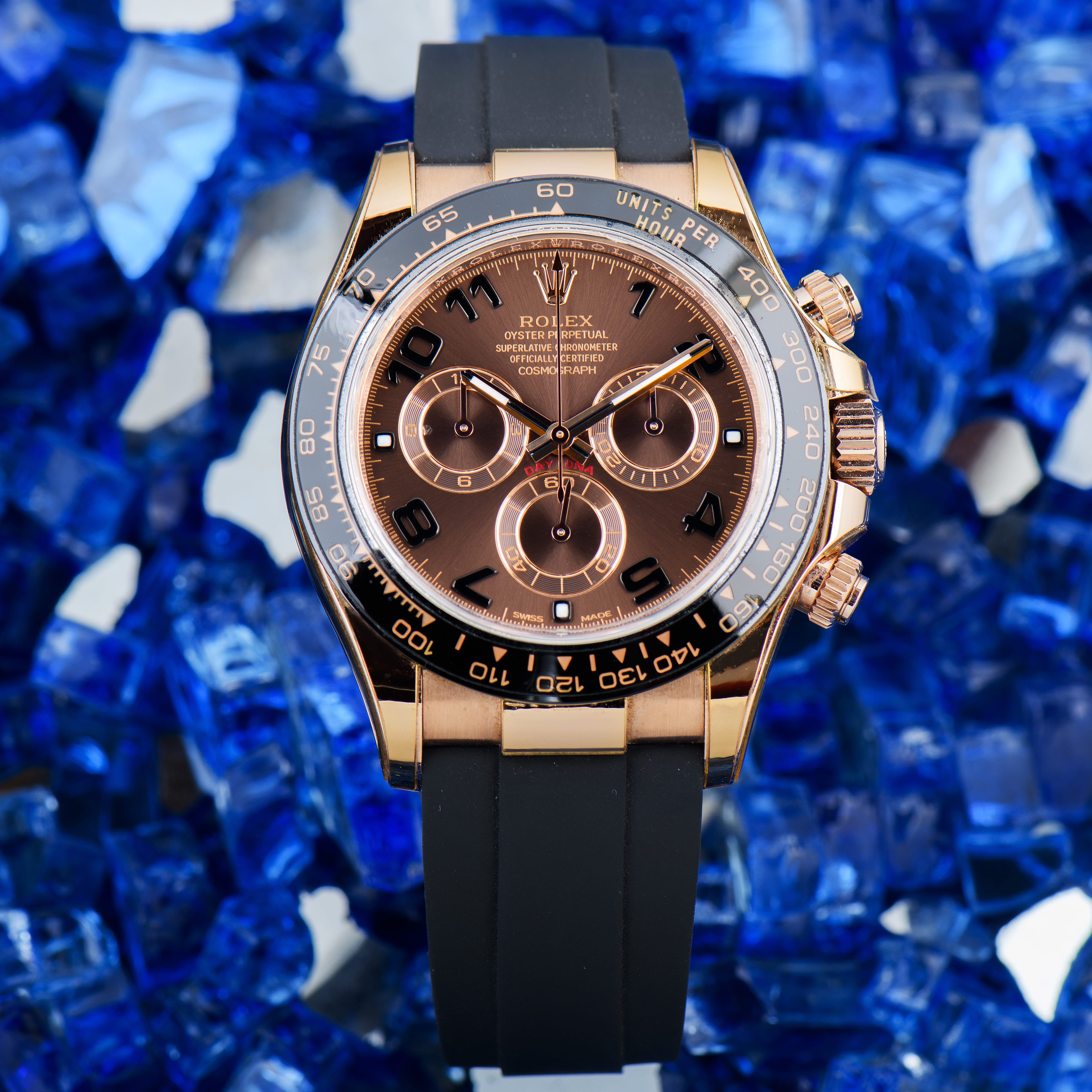 A genuine Rolex Cosmograph Daytona in Everose gold, shown dial-forward on a blue crushed-glass background